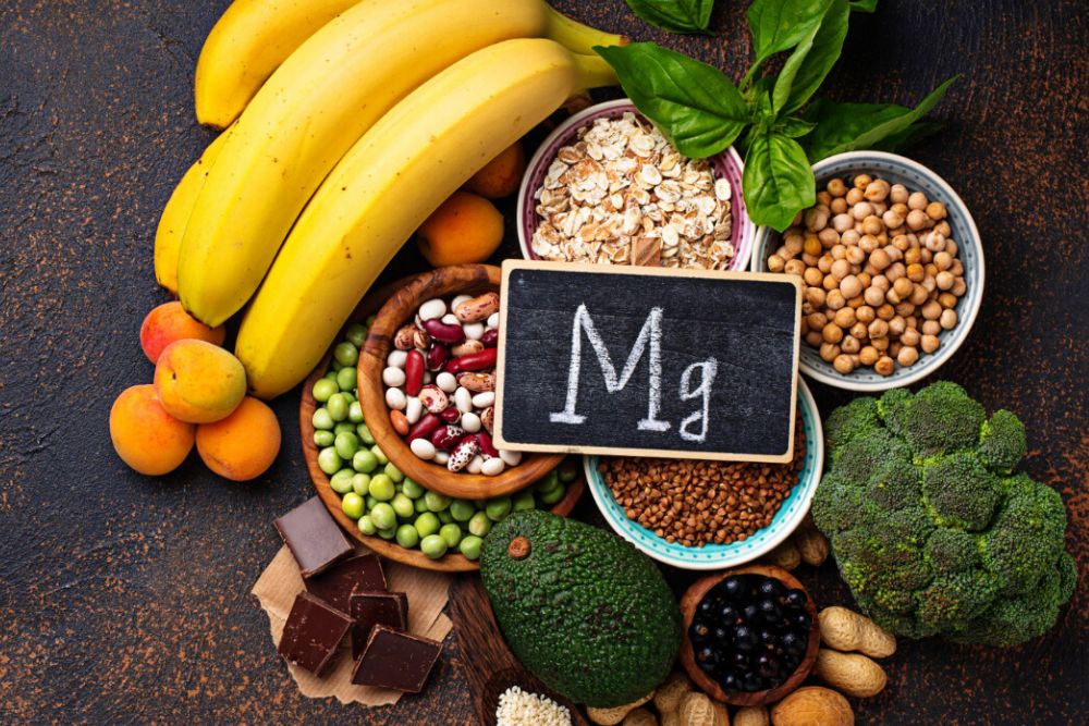 The picture shows the Magnesium Mg sign with fruits, vegetables and grains high in Magnesium
