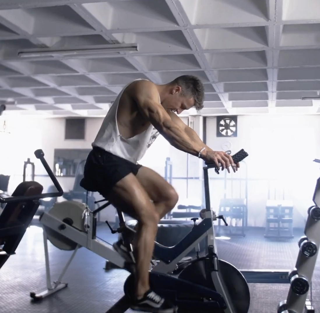 Man training on a stationary bike at the gym — supporting testosterone, energy, and motivation